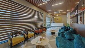 A modern lobby with wooden slatted blinds, a reception desk, and seating areas with patterned upholstery. - Click Collection Aster Jaipur  Raja Park (Jaipur)