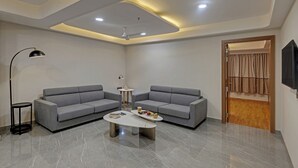 A modern living room with two grey sofas, a coffee table, a floor lamp, and a ceiling fan. - Click Collection Aster Jaipur  Raja Park (Jaipur)