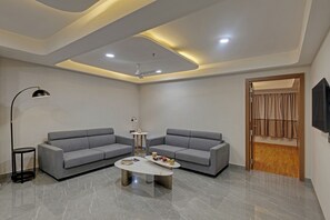 Uma sala de estar moderna com dois sofás cinzas, uma mesa de centro, um abajur e um ventilador de teto.