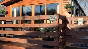 A wooden lodge with a sign reading 'Patricia's Lodge' and a warning sign about slippery decking.