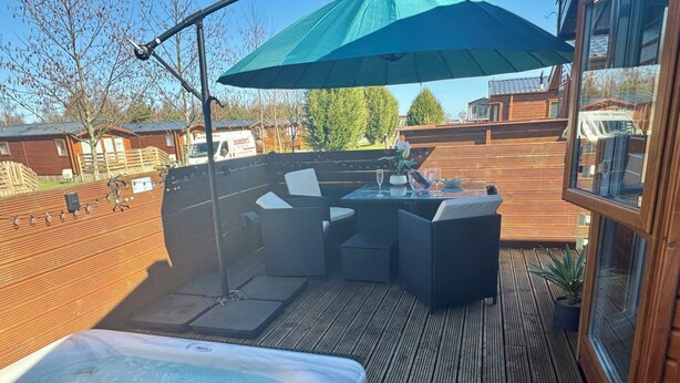 A hot tub, outdoor seating, and a wooden deck with a view of surrounding buildings.