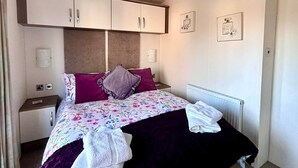 A bedroom with a bed, a nightstand, a dresser, and a radiator.