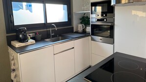 Una cocina moderna con horno empotrado, fogones y un lavamanos.