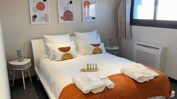A modern hotel room with a large bed, bedside tables, wall art, and a window with curtains.