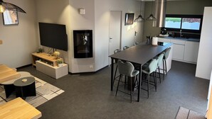 Una cocina moderna con comedor, televisor de pantalla plana e iluminación colgante.