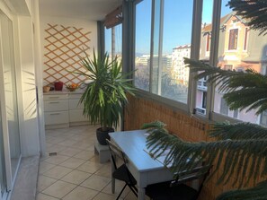 Ein Balkon mit Blick auf Gebäude, einer Topfpflanze, einem Tisch und einem Stuhl.