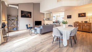 Een ruime woonkamer met een bank, eettafel en balkon.