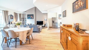 Een moderne woonkamer met een eethoek, keuken en televisie.