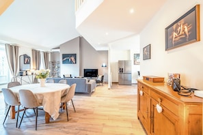 A modern living room with a dining area, a kitchen, and a TV. - Superb 125m2 duplex apartment with air-conditioning in the heart of Lyon's city center. (Lyon)