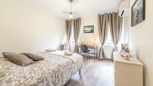 Een slaapkamer met een bed, een bureau, een stoel, een radiator en een raam met gordijnen.