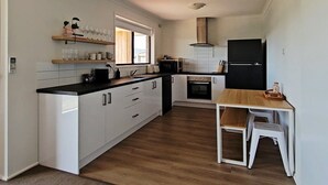 Una cocina moderna con armarios blancos, encimera negra y una mesa de comedor de madera.