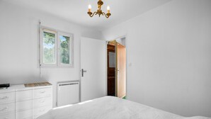 A bedroom with a bed, a dresser, a window, and a door leading to a closet. - Beautiful 2-Bedroom Apartment in Green Estate with Shared Pool, Balcony & Wi-Fi (Six-Fours-les-Plages)