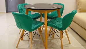 Un coin repas avec une table ronde et quatre chaises, un canapé et une porte en arrière-plan.