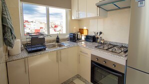 Une cuisine de taille réduite, dotée d’une fenêtre, d’une cuisinière, d’un évier et d’un réfrigérateur.