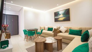 Un salon moderne avec un canapé, deux petites tables rondes en bois, une table à manger avec des chaises et un tableau accroché au mur.