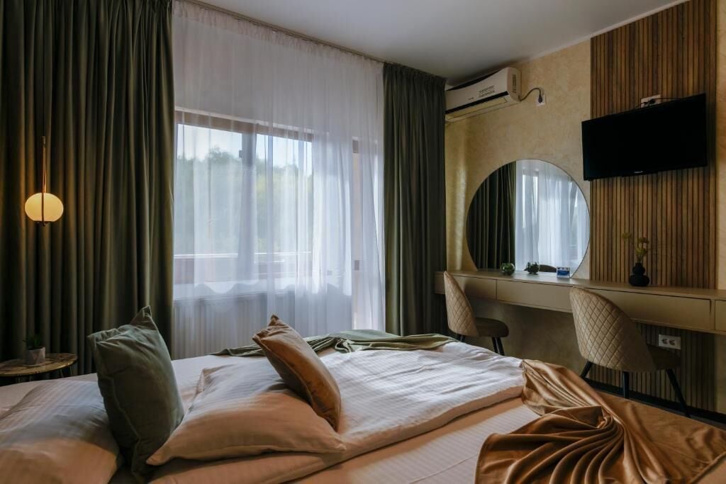 A hotel room with a bed, a desk, a chair, a television, and a large mirror.