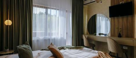 A hotel room with a bed, a desk, a chair, a television, and a large mirror.