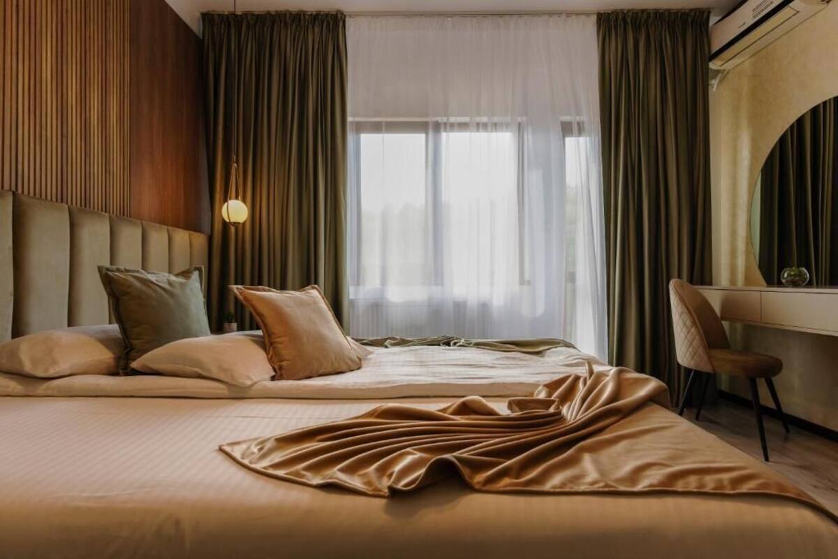 Ein Hotelzimmer mit Bett, Schreibtisch und einem großen Fenster mit Vorhängen.