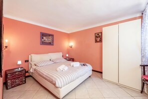 A bedroom with a bed, two bedside tables, a wardrobe, and two wall-mounted lights. - Genova House Via Caffaro (Genoa)