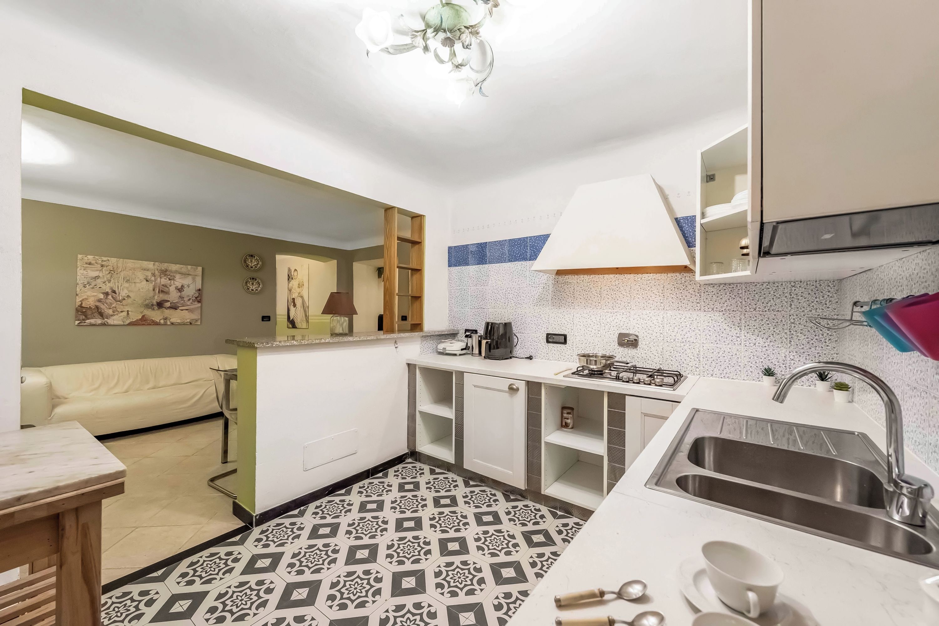 A compact kitchen with a patterned floor, a sink, and a dining area with a table and chairs.