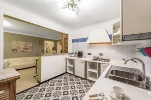 Eine kleine Küche mit einem gemusterten Boden, einer Spüle und einer Essecke mit Tisch und Stühlen.
