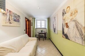 A hallway with a white sofa, a dining table with chairs, and artwork on the walls. - Genova House Via Caffaro (Genoa)