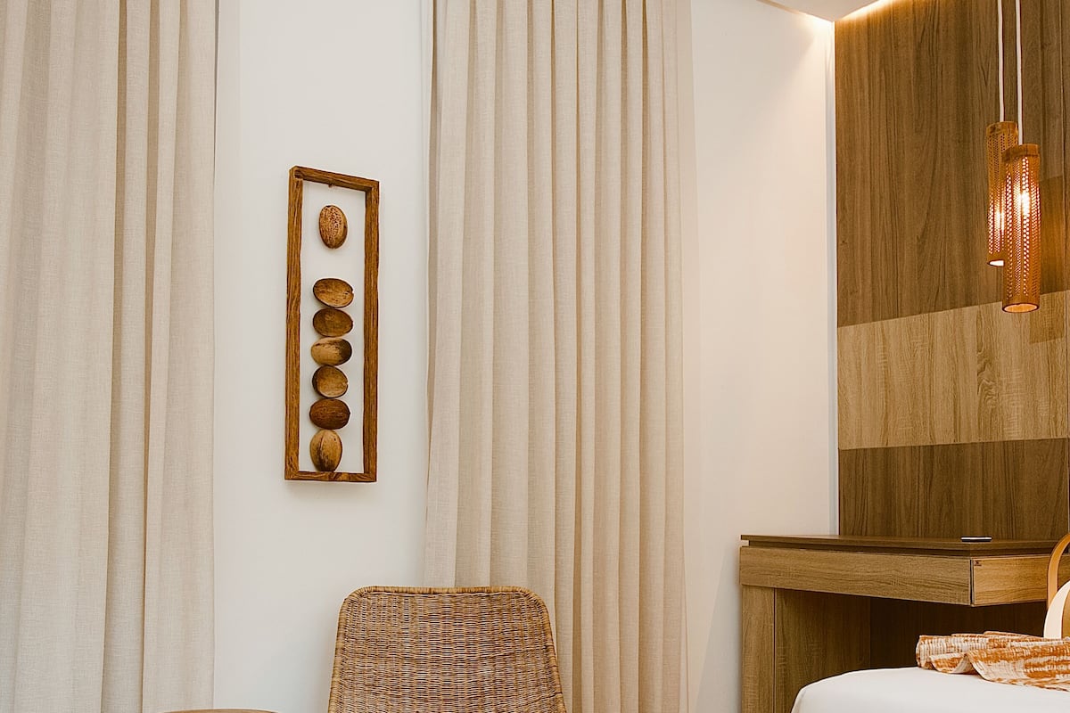 Un dormitorio moderno con cama, una silla, una mesita y una lámpara fijada a la pared.