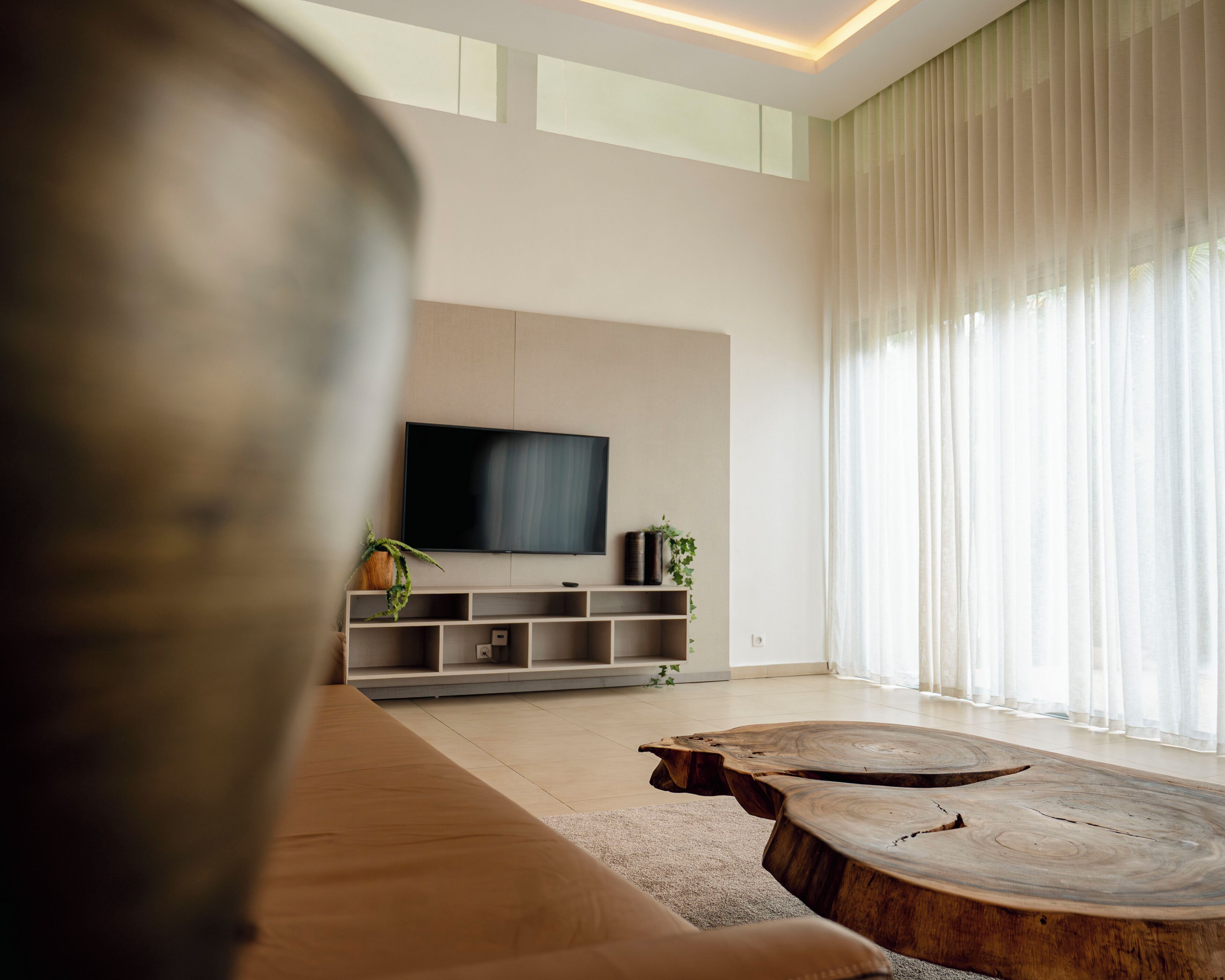 A modern living room with a flat-screen TV, a wooden coffee table, and a sofa.