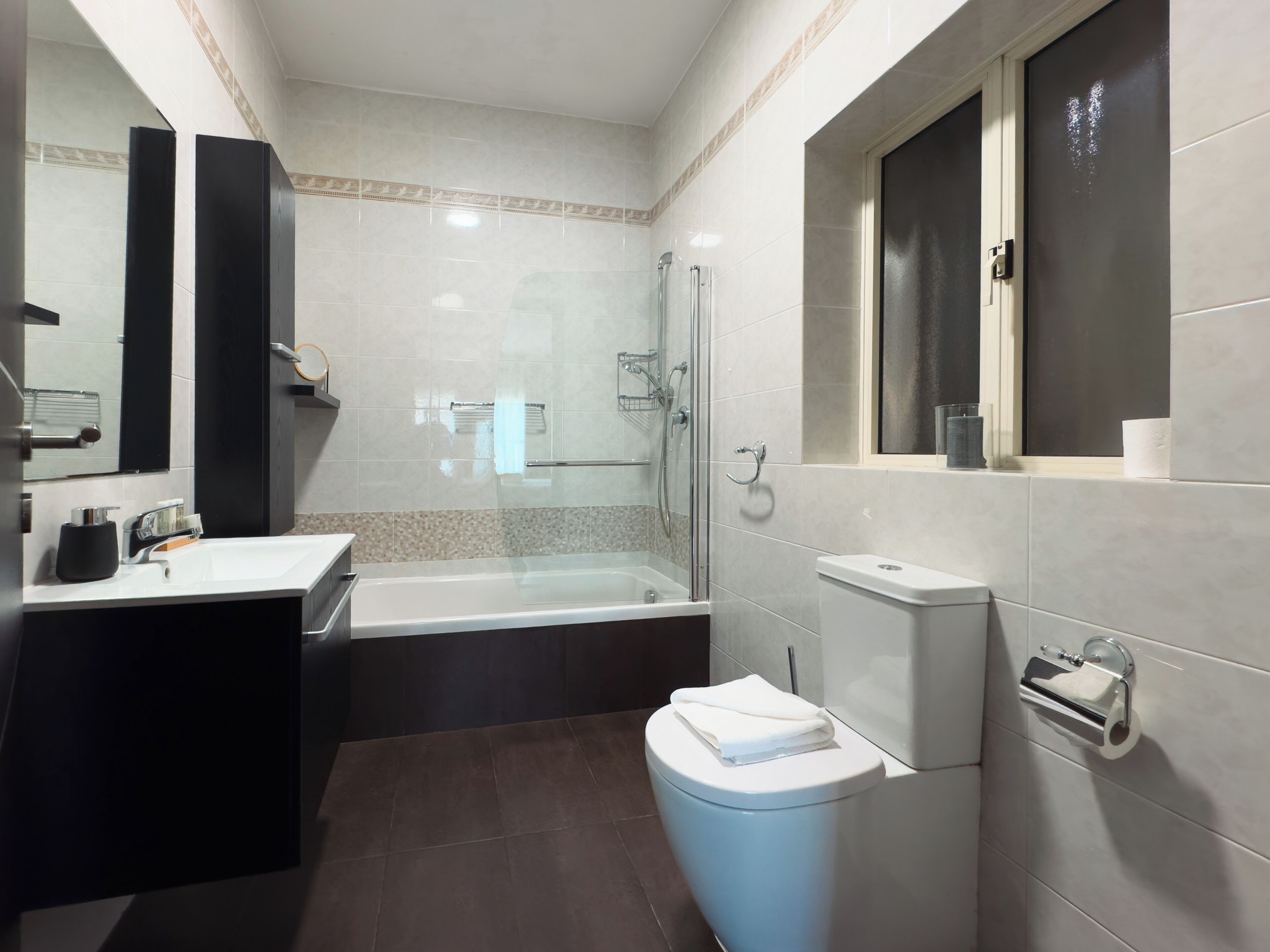 Ein modernes Badezimmer mit Badewanne, Toilette und einer Duschkabine aus Glas.
