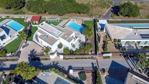An aerial view of a modern hotel with multiple swimming pools, a golf course, and a large building with a red roof. - Villa PinkBirdie de Luxe. Frontline Golf Las Colinas Piscine Rooftop Bali Lounge (Dehesa de Campoamor)