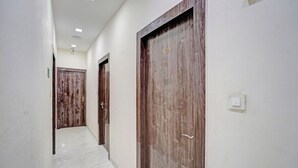 A hallway with wooden doors, a tiled floor, and a light switch on the wall.