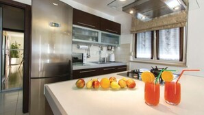 A modern kitchen with stainless steel appliances, a large island with fruits and drinks, and a window with curtains. - Villa Greta - Jadreški by Villas Guide (Jadreški)