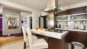A modern kitchen with a central island, built-in appliances, and a bar area with bottles. - Villa Greta - Jadreški by Villas Guide (Jadreški)