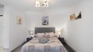 A bedroom with a bed, bedside tables, a chandelier, and wall art.