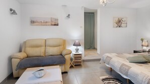 Une pièce confortable avec un canapé, une petite table sur laquelle se trouve un bol, une lampe et un lit avec des oreillers.