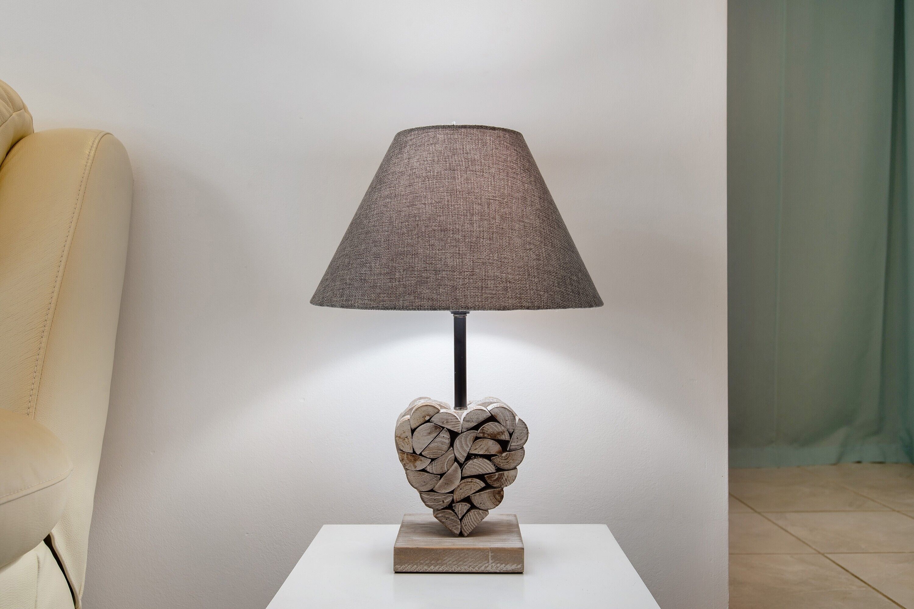 Eine Lampe mit einer strukturierten Schirm und einem herzförmigen Sockel auf einem weißen Tisch.