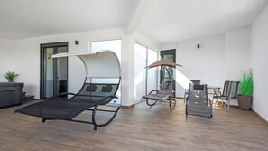 A modern living room with a large bed, a swing chair, and a dining area. - Villa Pinus by Villas Guide (Crvar)
