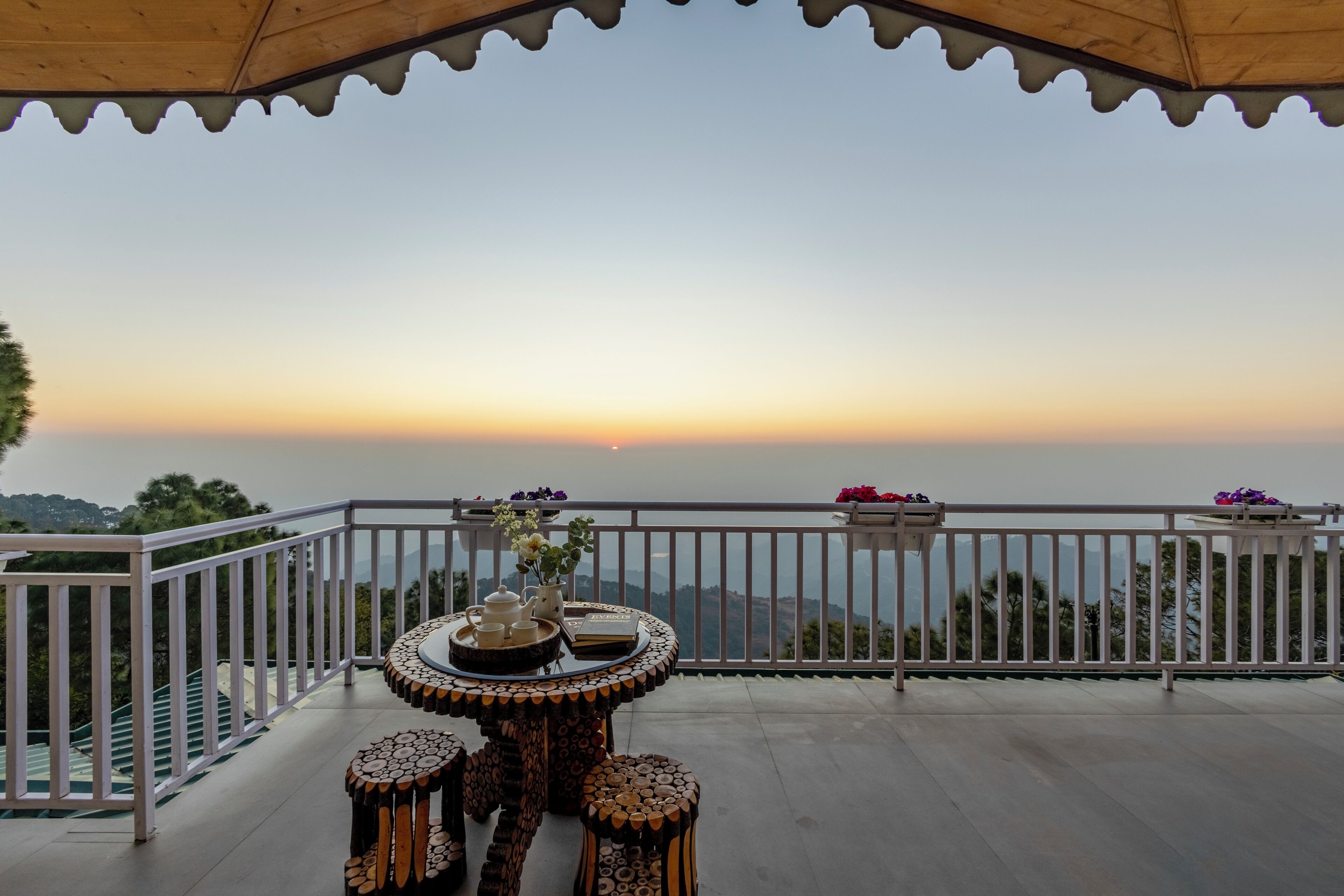 A balcony with a table and chairs, a railing, and a view of the horizon.