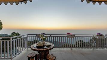 A balcony with a table and chairs, a railing, and a view of the horizon.