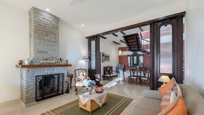 Un salon doté d’une cheminée, d’un canapé, d’un coin repas et d’un escalier menant à l’étage supérieur.