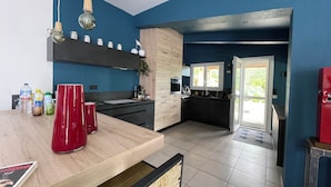 A modern kitchen with a wooden countertop, a red vase, and a view to the outside. - Bed and breakfast in the south of France (Entre-Vignes)