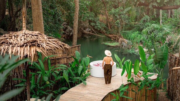 A wooden deck leading to a circular hot tub with a thatched-roof structure nearby. - Hatchu khaoyai (Pak Chong)