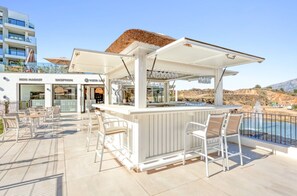 A rooftop bar with white bar stools, a reception area, and a poolside view. - La Calma | Terrace - pool - gym (Mijas)