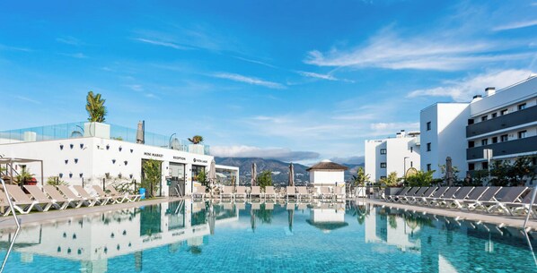 A poolside view with lounge chairs, a reception area, and a mountain backdrop. - La Calma | Terrace - pool - gym (Mijas)