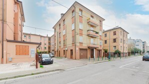 A multi-story residential building with a garage, parked cars, and a clear sky. - Casa Tatiana (Mestre)