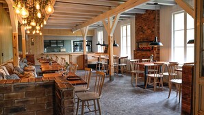 A restaurant with exposed wooden beams, brick walls, and hanging light fixtures. Tables and chairs are arranged for dining. - Norrkällan (Vännäs)