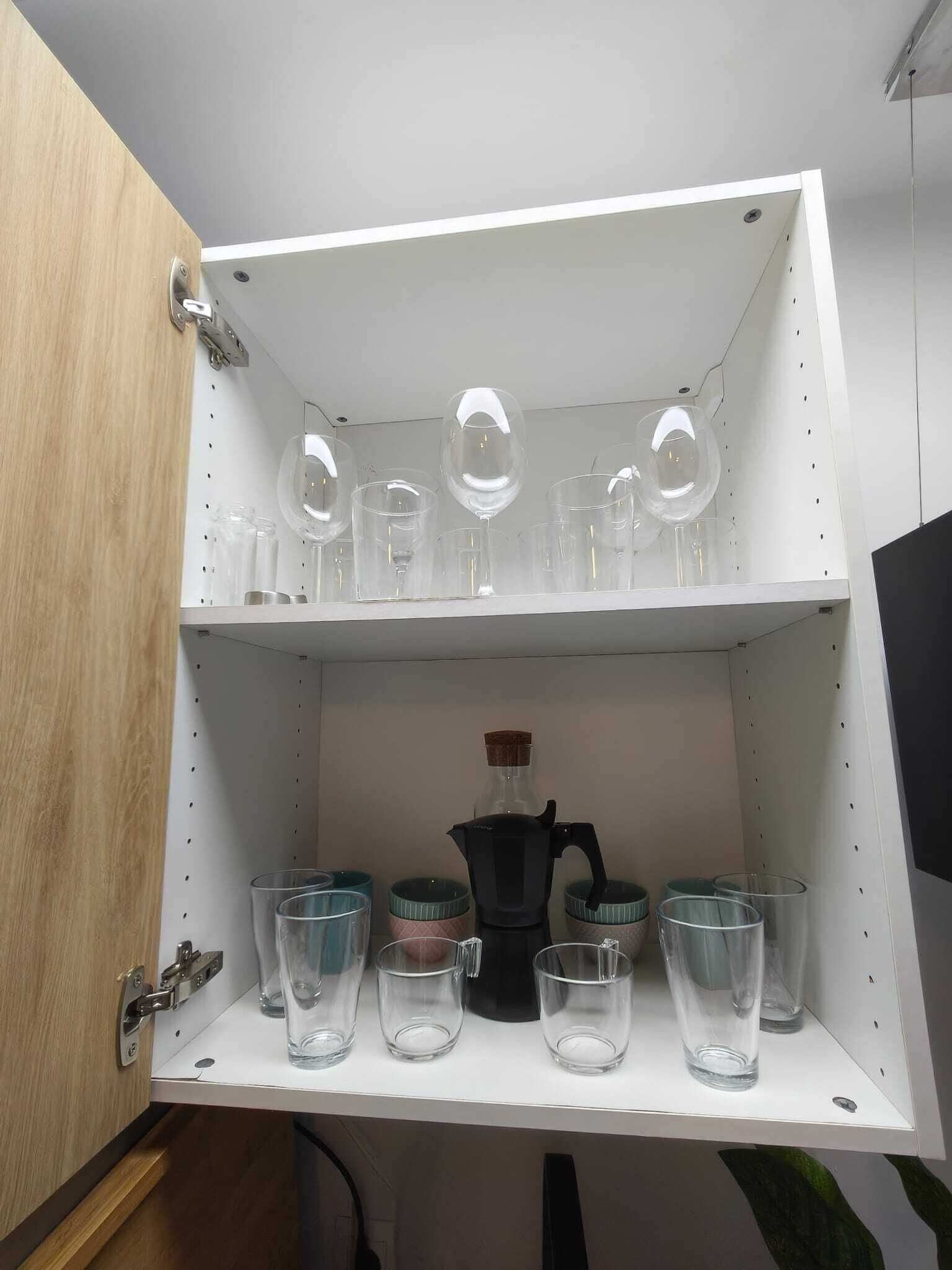 Un armario de cocina con repisas que contienen diferentes vasos y una cafetera.