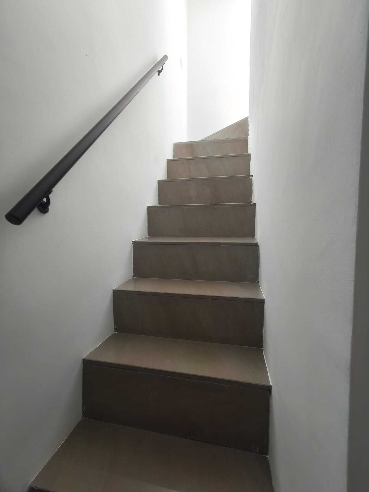A staircase with a handrail, leading to a landing.