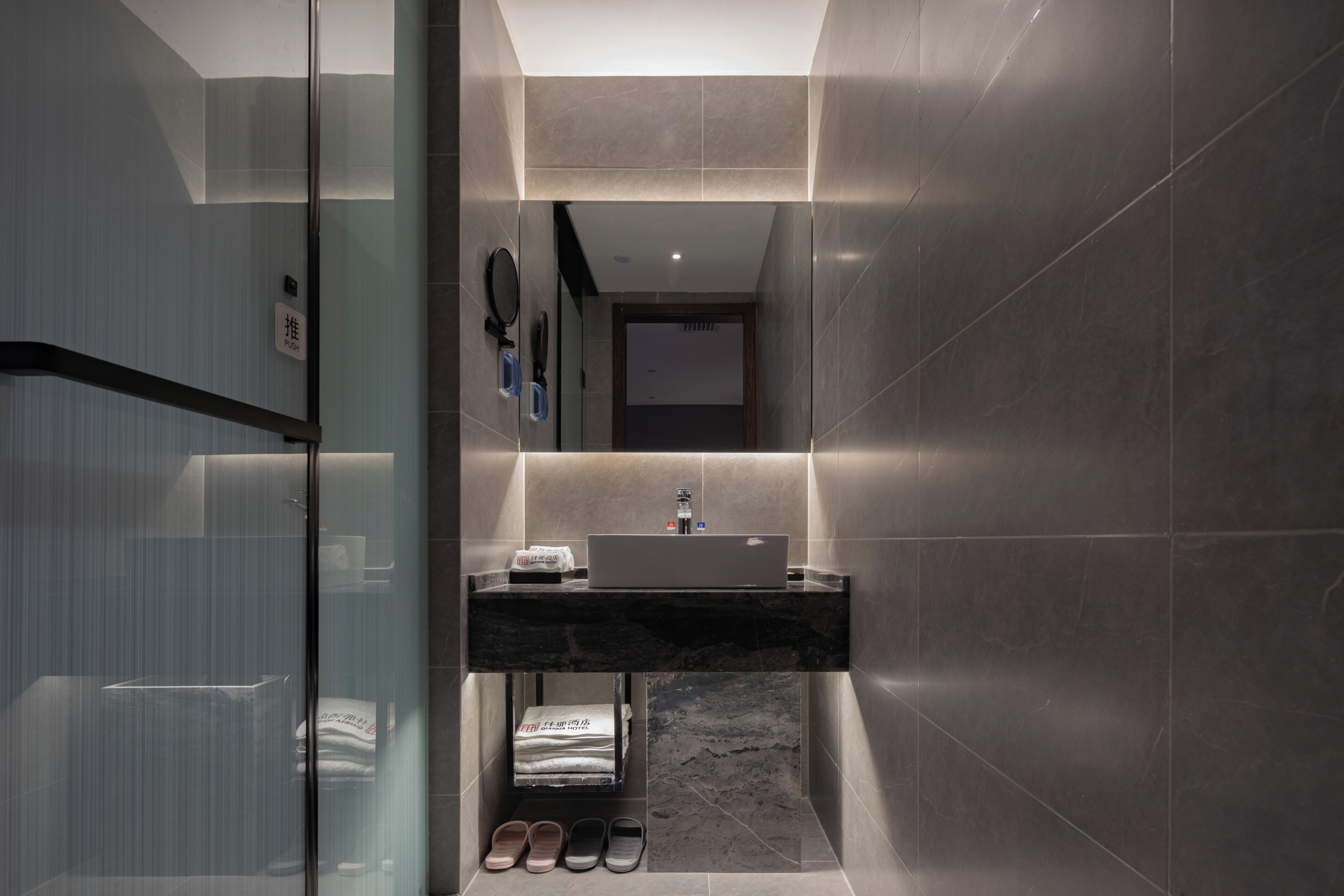A modern bathroom with a glass shower enclosure, a vanity with a sink, and a mirror.