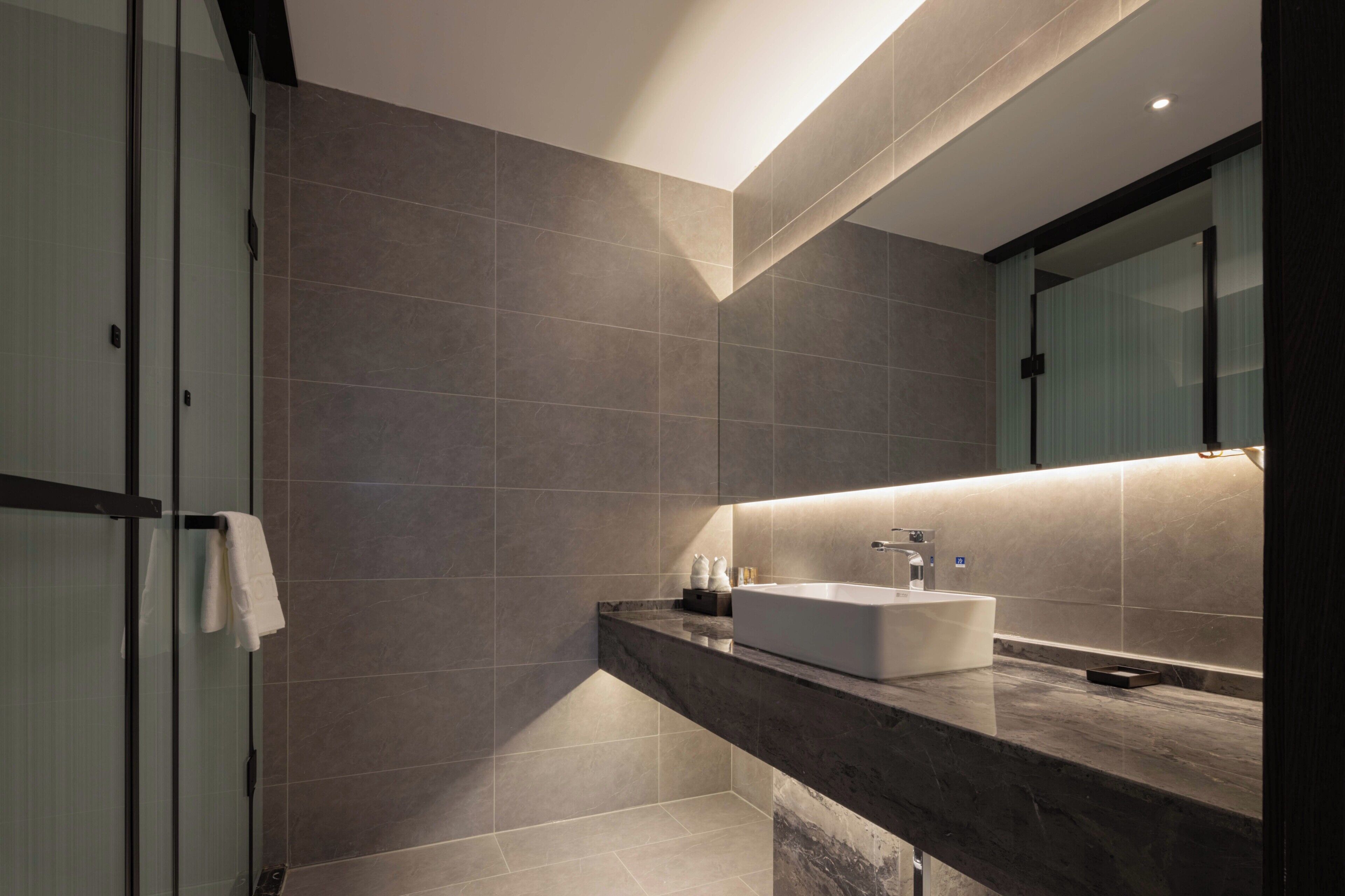 A modern bathroom with a large mirror, a white sink, and a glass shower enclosure.
